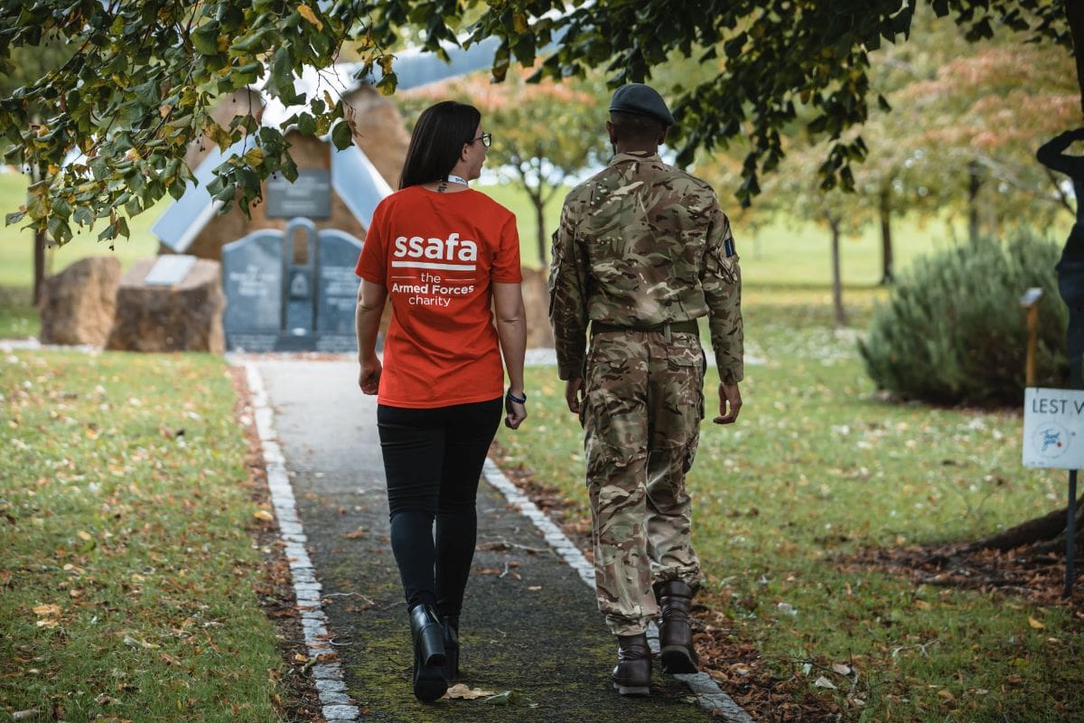 Woman wearing SSAFA t-shirt and male soldier walking with their back to the camera