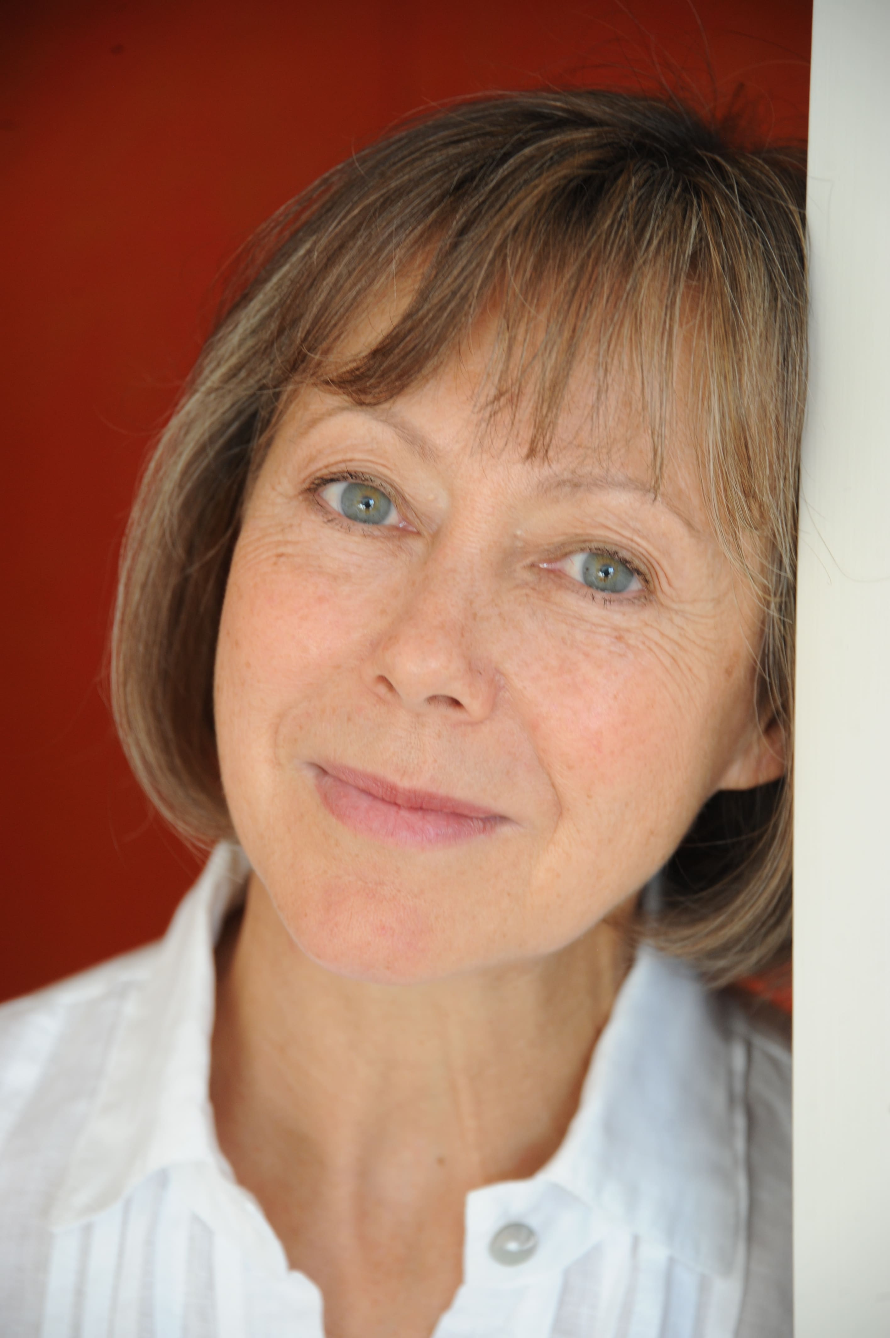 Portrait of a woman looking at the camera, leaning on a doorframe
